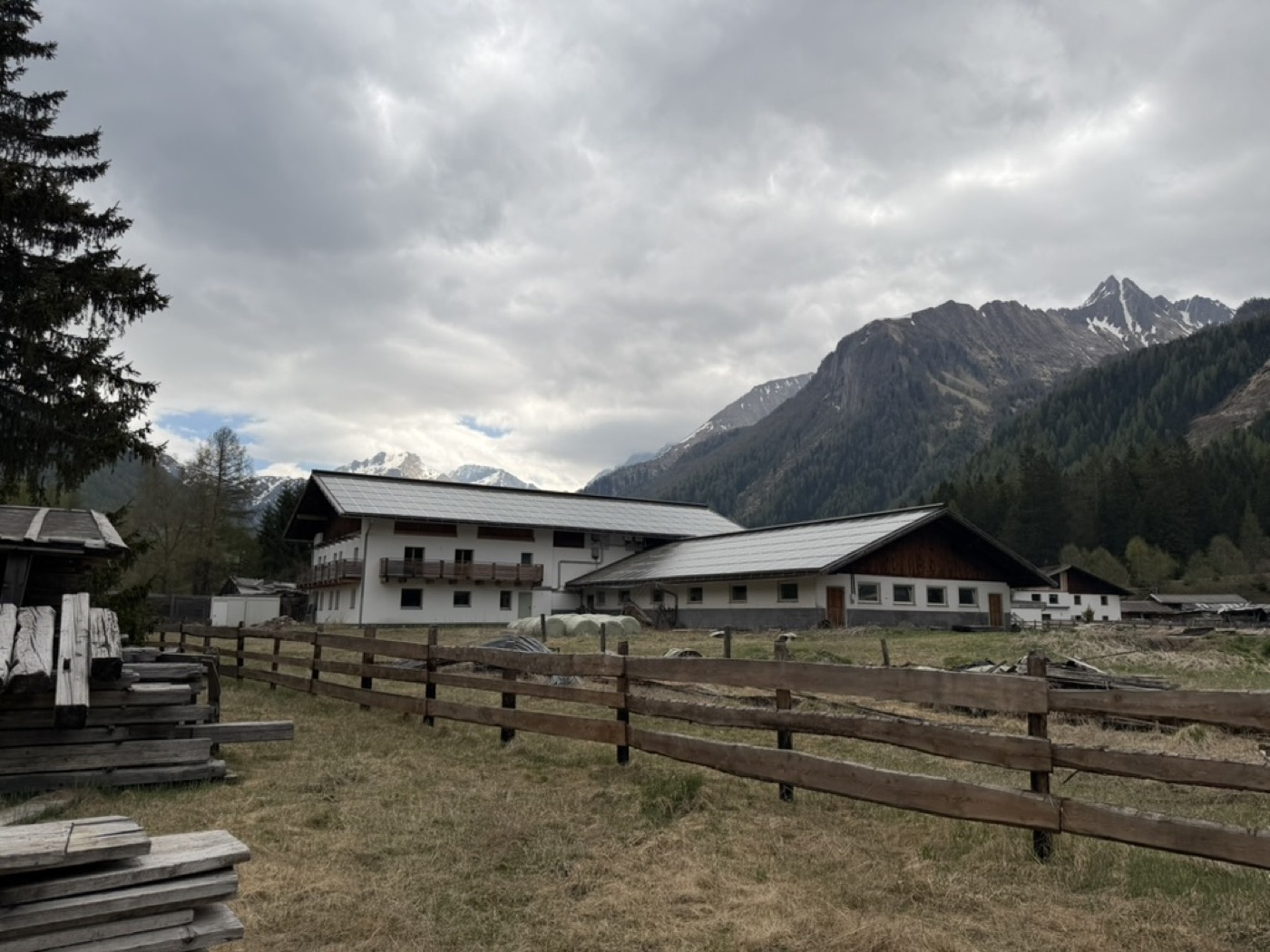 Knappenhof mit Bergpanorama und Holzzaun im Vordergrund